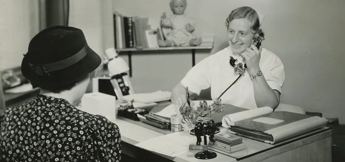 En svartvit bild på en sköterska som pratar i telefon. 
